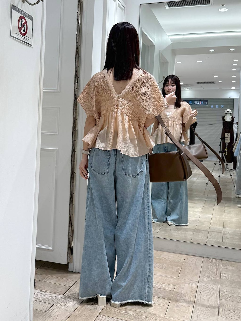 ブルー系のデニムパンツ、ブラウン系のショルダーバッグ、ホワイト系のサンダルを着用したレディースの春コーディネートの3枚目の写真