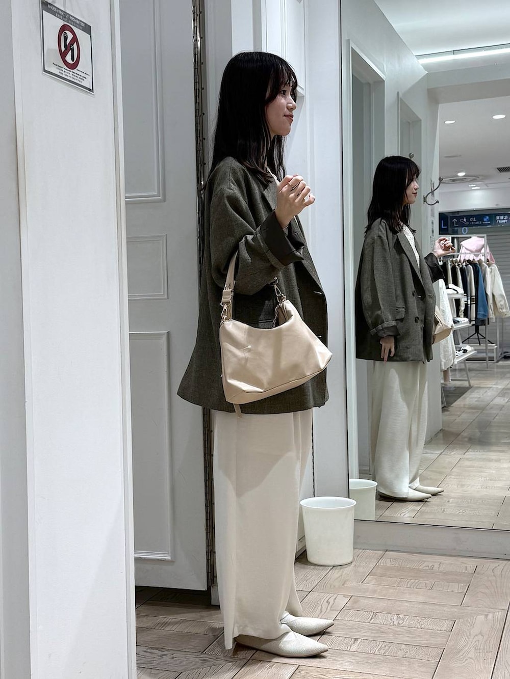 ブラウン系のテーラードジャケット、ベージュ系のショルダーバッグ、ホワイト系のパンプスを着用したレディースの春コーディネートの2枚目の写真