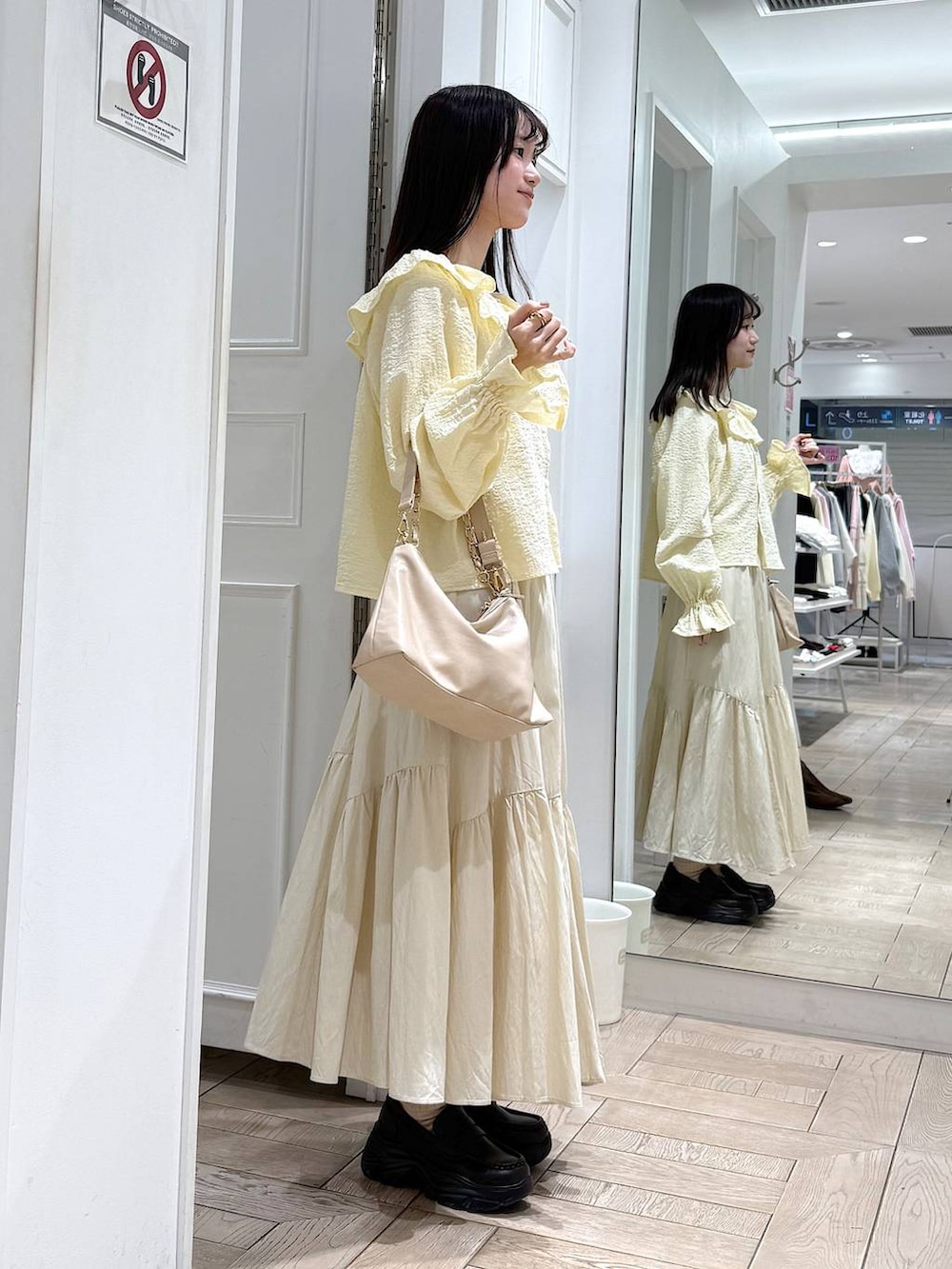 ベージュ系のショルダーバッグ、ブラウン系のローファー、イエロー系のシャツ/ブラウスを着用したレディースの冬コーディネートの2枚目の写真