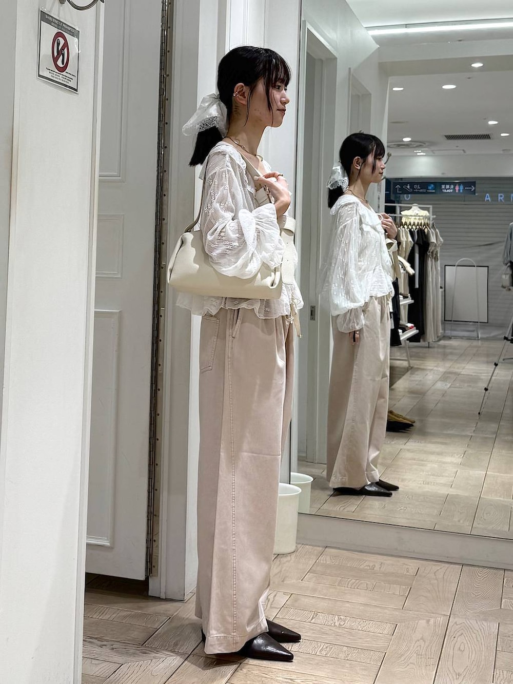 ピンク系のデニムパンツ、ブラウン系のサンダル、ホワイト系のショルダーバッグを着用したレディースの春コーディネートの2枚目の写真