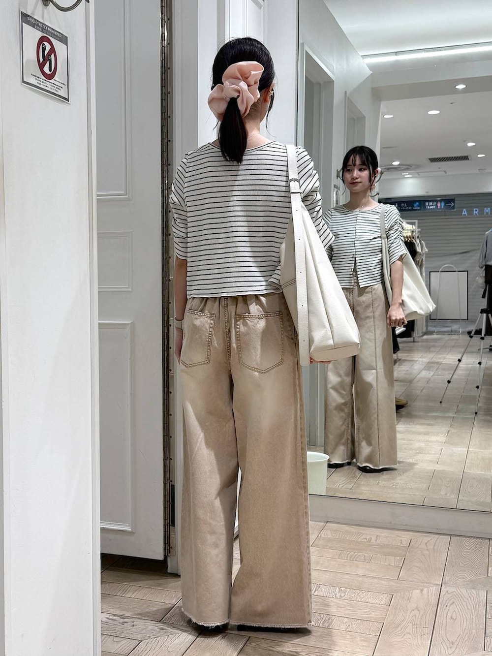 ホワイト系のショルダーバッグ、オレンジ系のデニムパンツ、ブラウン系のサンダルを着用したレディースの春コーディネートの3枚目の写真