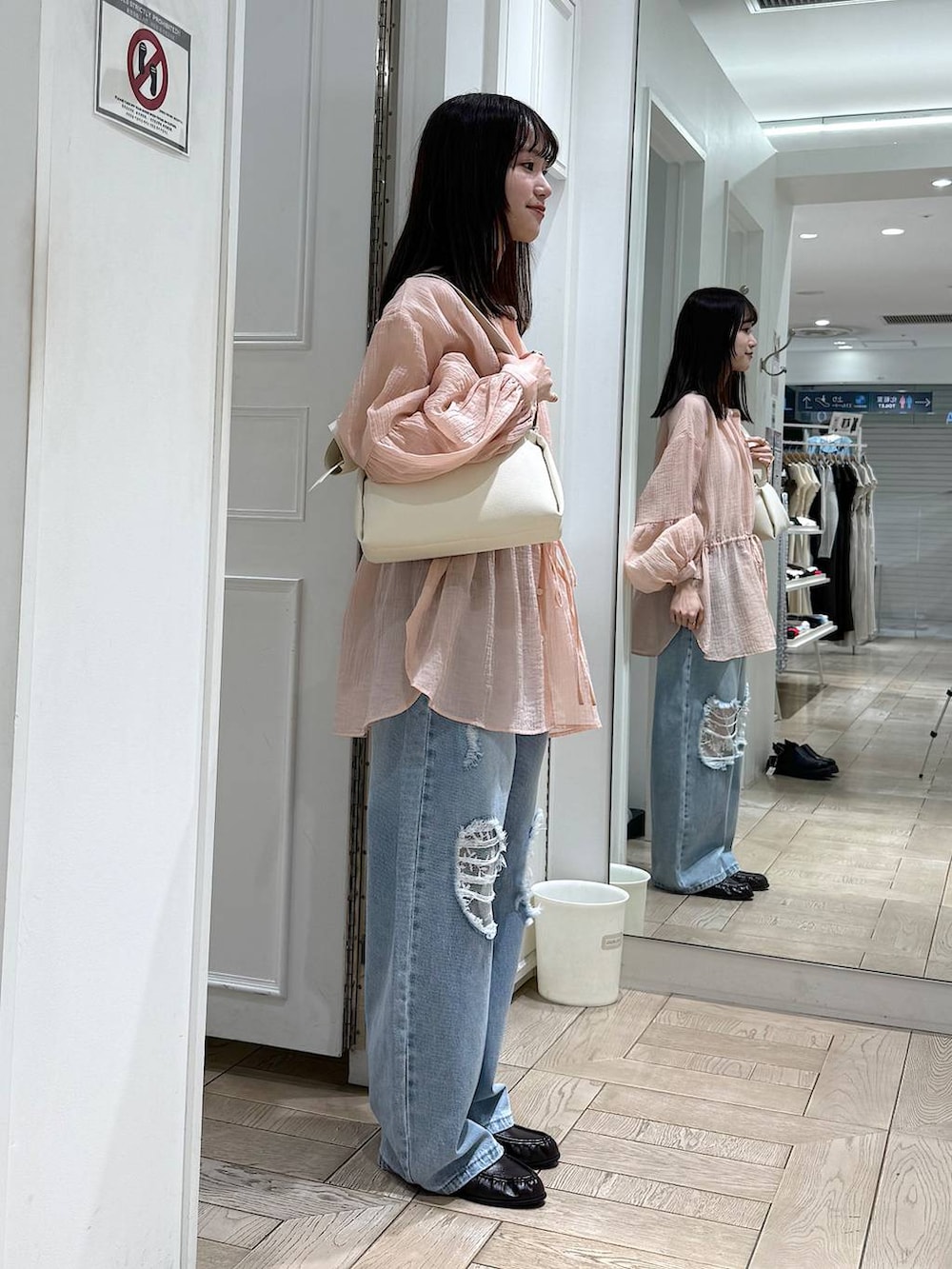 ブルー系のデニムパンツ、ブラウン系のローファー、ホワイト系のショルダーバッグを着用したレディースの春コーディネートの2枚目の写真