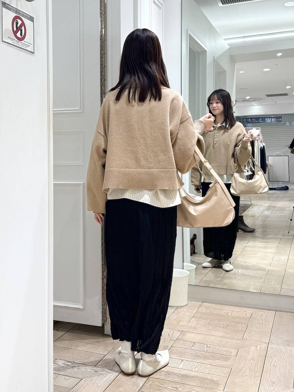 ベージュ系のショルダーバッグ、ホワイト系のパンプス、ブラック系のスカートを着用したレディースの冬コーディネートの3枚目の写真