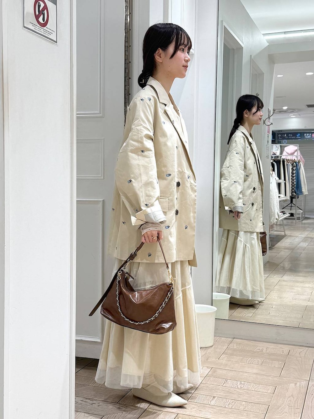 ブラウン系のショルダーバッグ、ホワイト系のパンプス、ホワイト系のスカートを着用したレディースの冬コーディネートの2枚目の写真