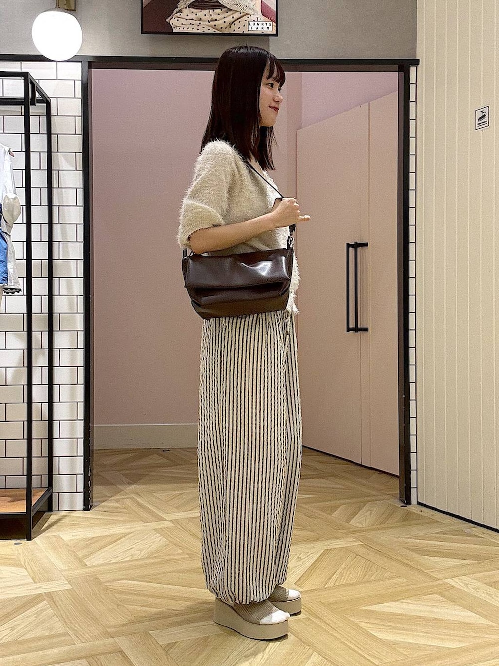 ブラウン系のショルダーバッグ、ホワイト系のカーディガン/ボレロ、ホワイト系のサンダルを着用したレディースの夏コーディネートの2枚目の写真