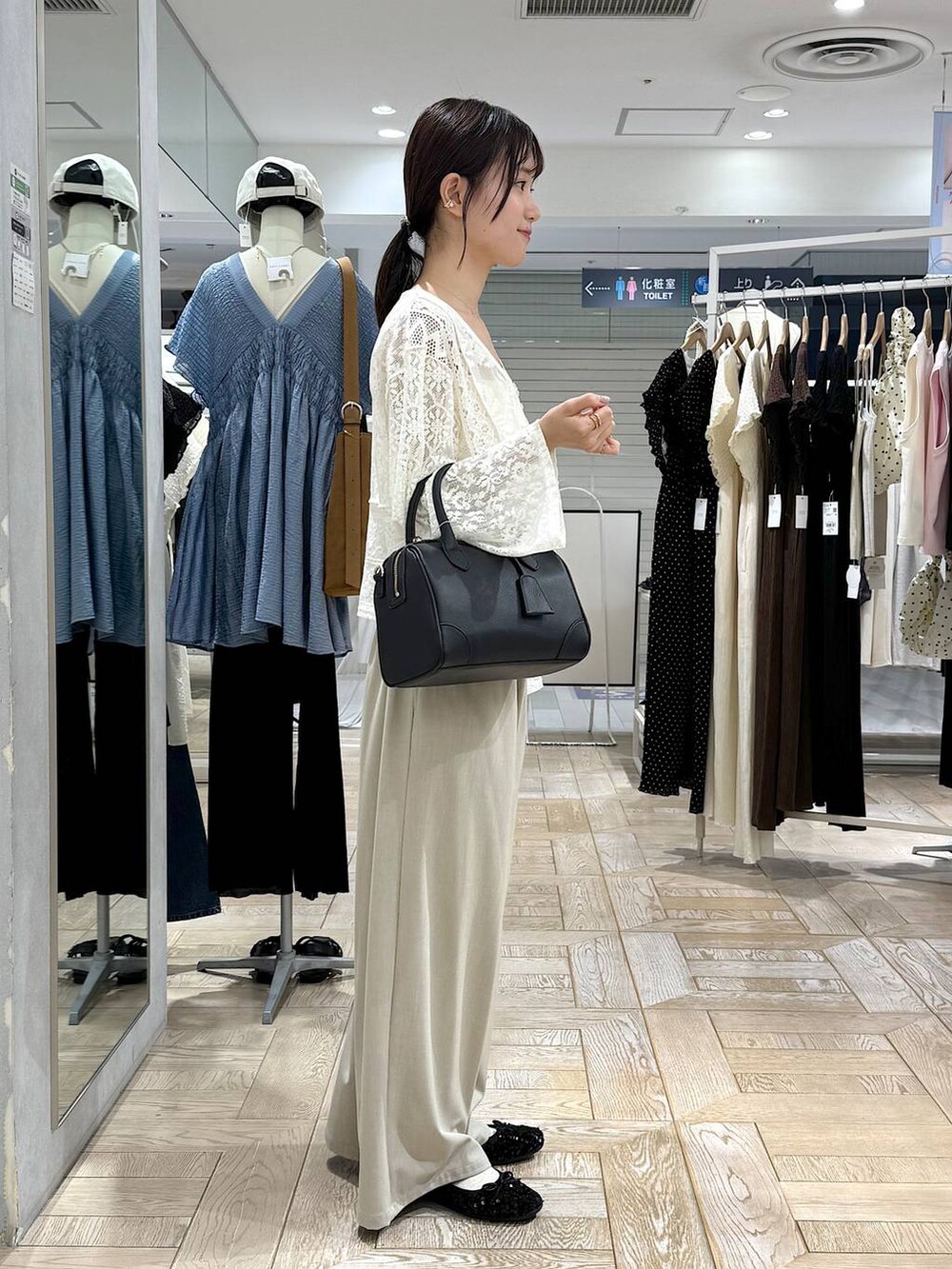 ブラック系のショルダーバッグ、ホワイト系のカーディガン/ボレロ、ゴールド系のバレッタ/ヘアクリップを着用したレディースの秋コーディネートの2枚目の写真