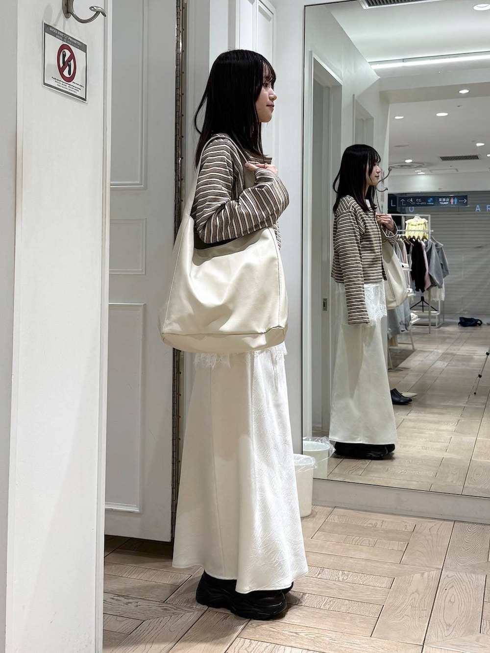 ホワイト系のスカート、ホワイト系のショルダーバッグ、ブラウン系のローファーを着用したレディースの春コーディネートの2枚目の写真