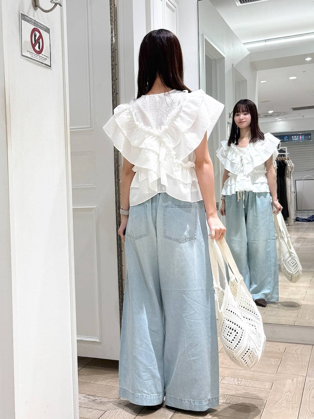ブラウン系のサンダル、ブルー系のデニムパンツ、ホワイト系のトートバッグを着用したレディースの夏コーディネートの3枚目の写真