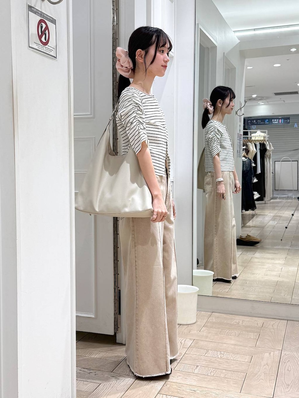 ホワイト系のショルダーバッグ、オレンジ系のデニムパンツ、ブラウン系のサンダルを着用したレディースの春コーディネートの2枚目の写真