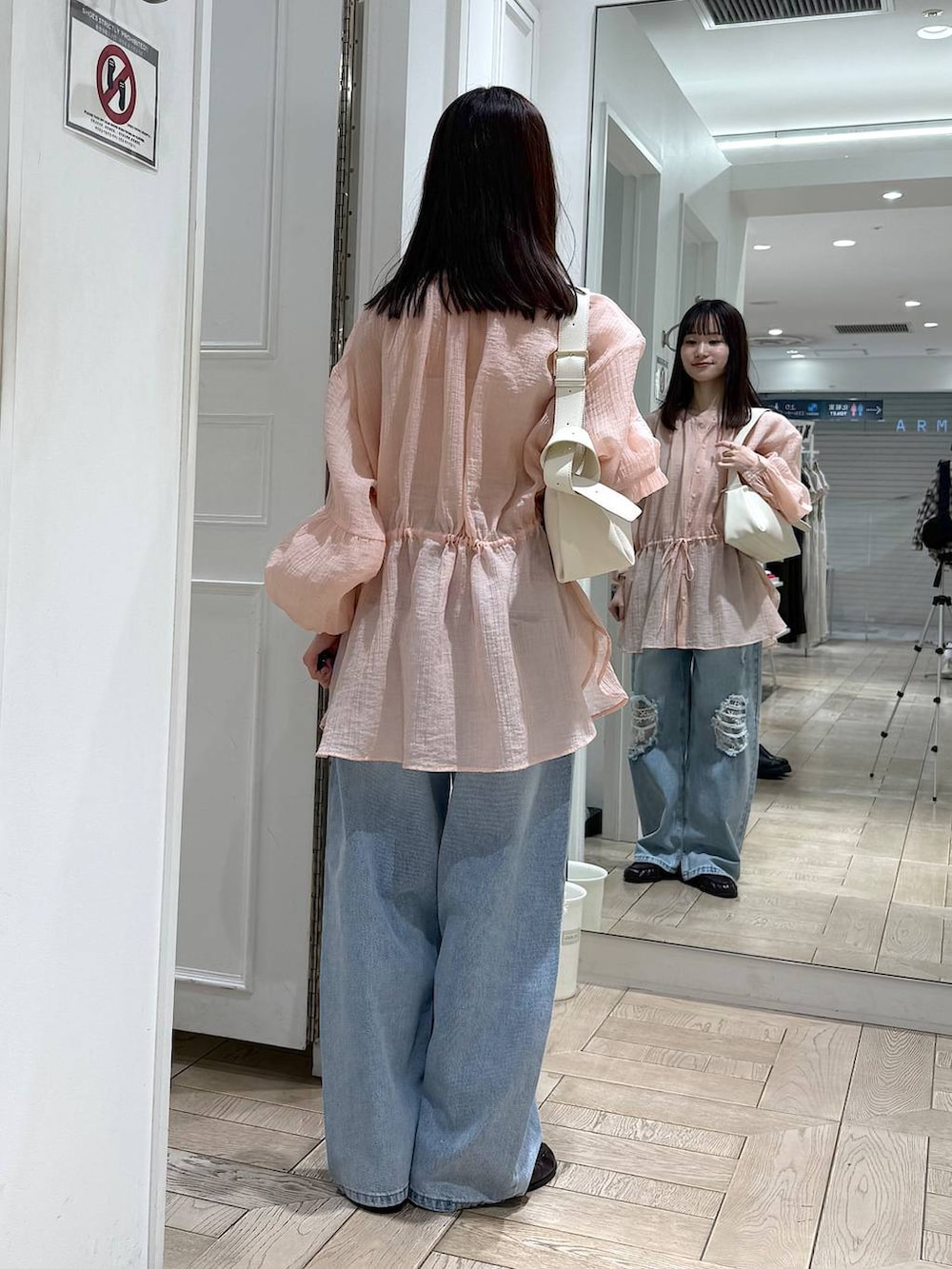 ブルー系のデニムパンツ、ブラウン系のローファー、ホワイト系のショルダーバッグを着用したレディースの春コーディネートの3枚目の写真