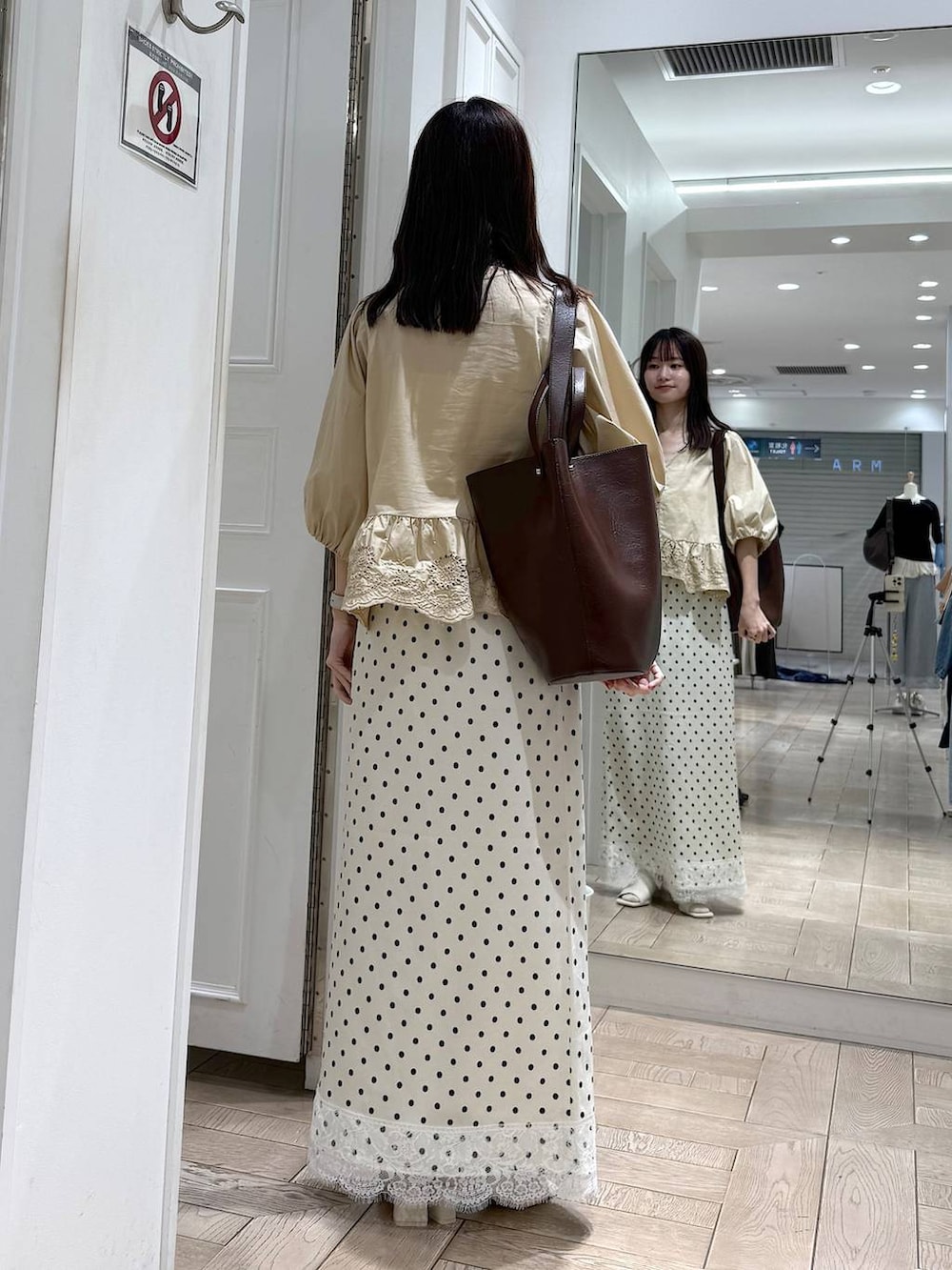 ベージュ系のシャツ/ブラウス、ブラウン系のトートバッグ、ホワイト系のサンダルを着用したレディースの夏コーディネートの3枚目の写真