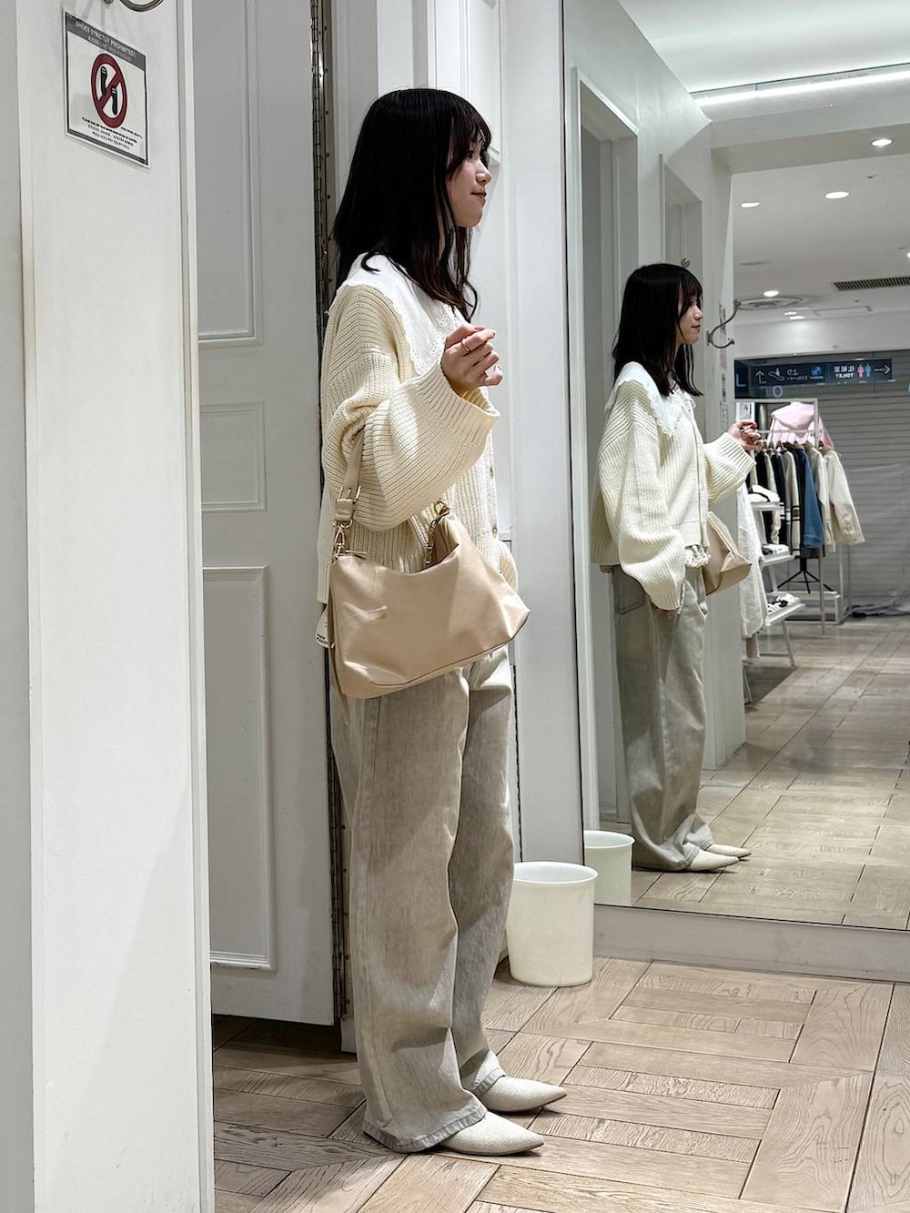 ベージュ系のデニムパンツ、ベージュ系のショルダーバッグ、ホワイト系のパンプスを着用したレディースの冬コーディネートの2枚目の写真