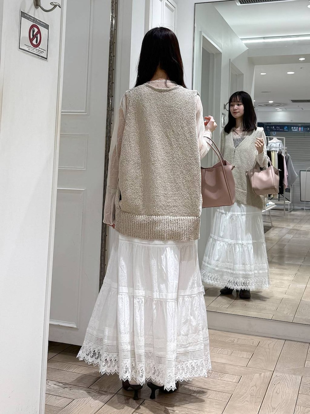 ピンク系のショルダーバッグ、ブラウン系のサンダル、ホワイト系のベストを着用したレディースの春コーディネートの3枚目の写真