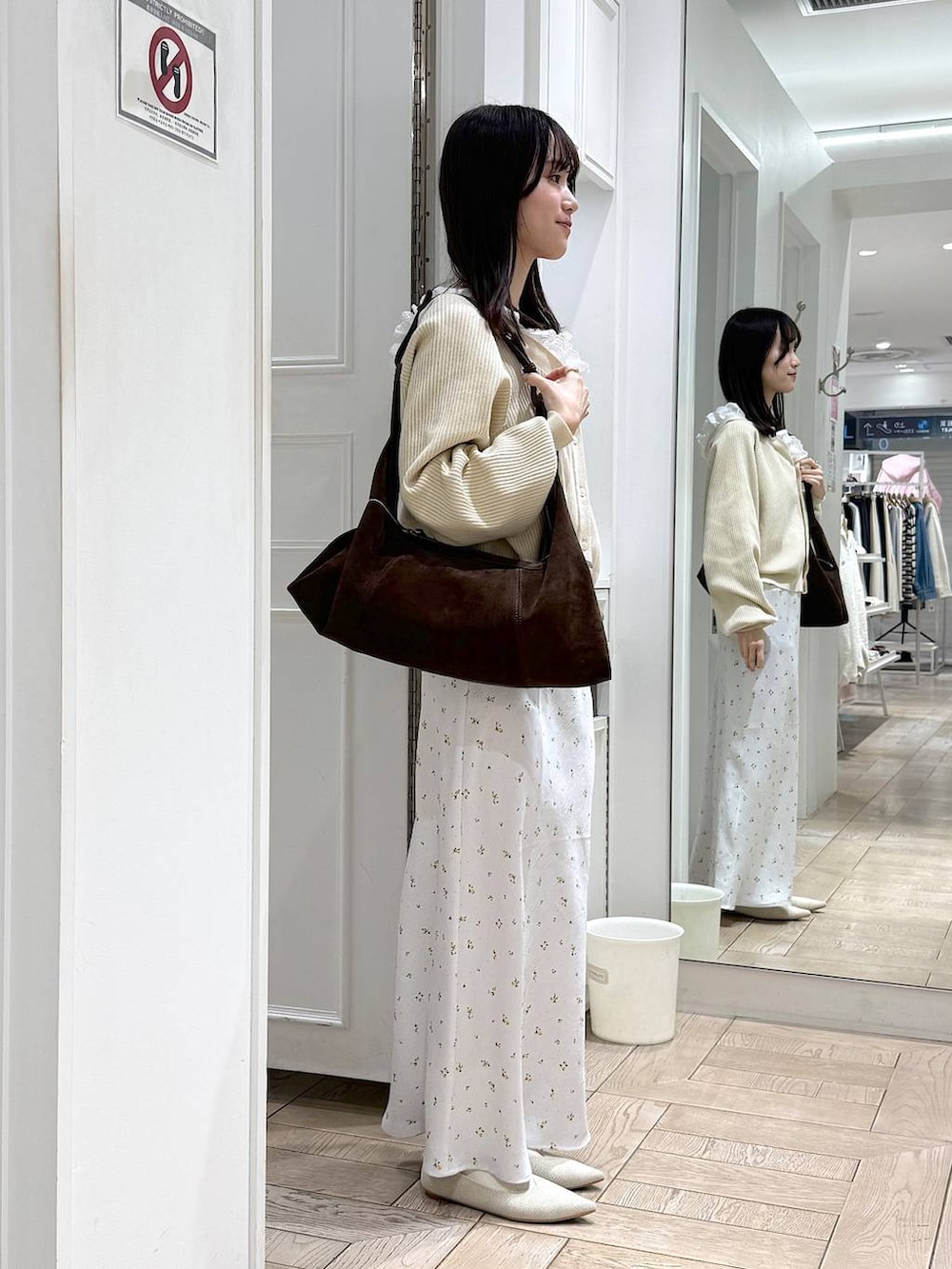 ホワイト系のスカート、ホワイト系のパンプス、ブラウン系のショルダーバッグを着用したレディースの冬コーディネートの2枚目の写真