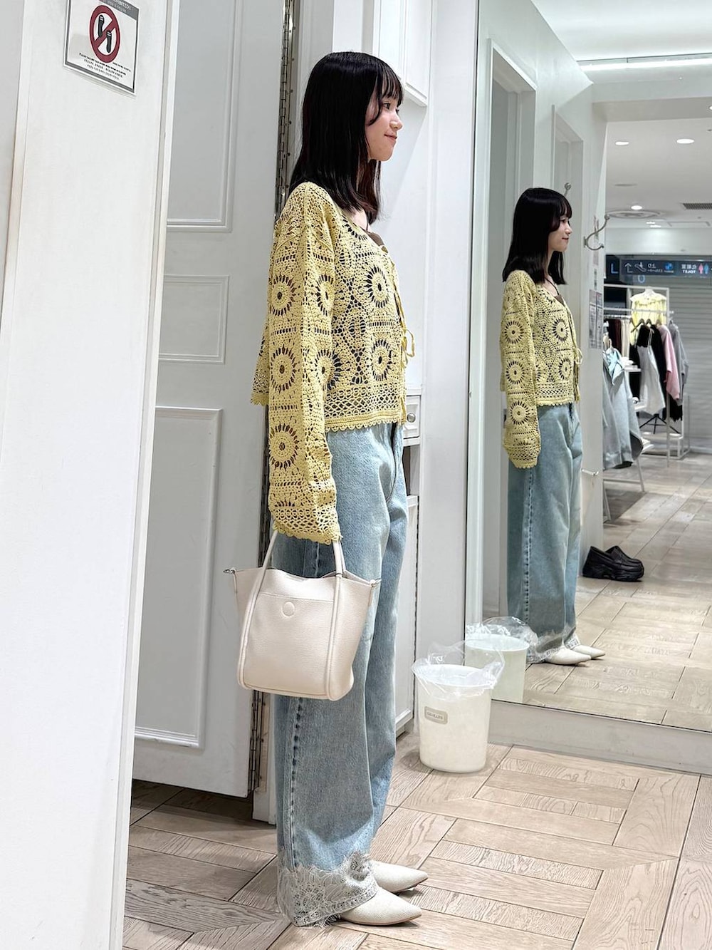 ホワイト系のショルダーバッグ、ブルー系のデニムパンツ、ホワイト系のパンプスを着用したレディースの春コーディネートの2枚目の写真