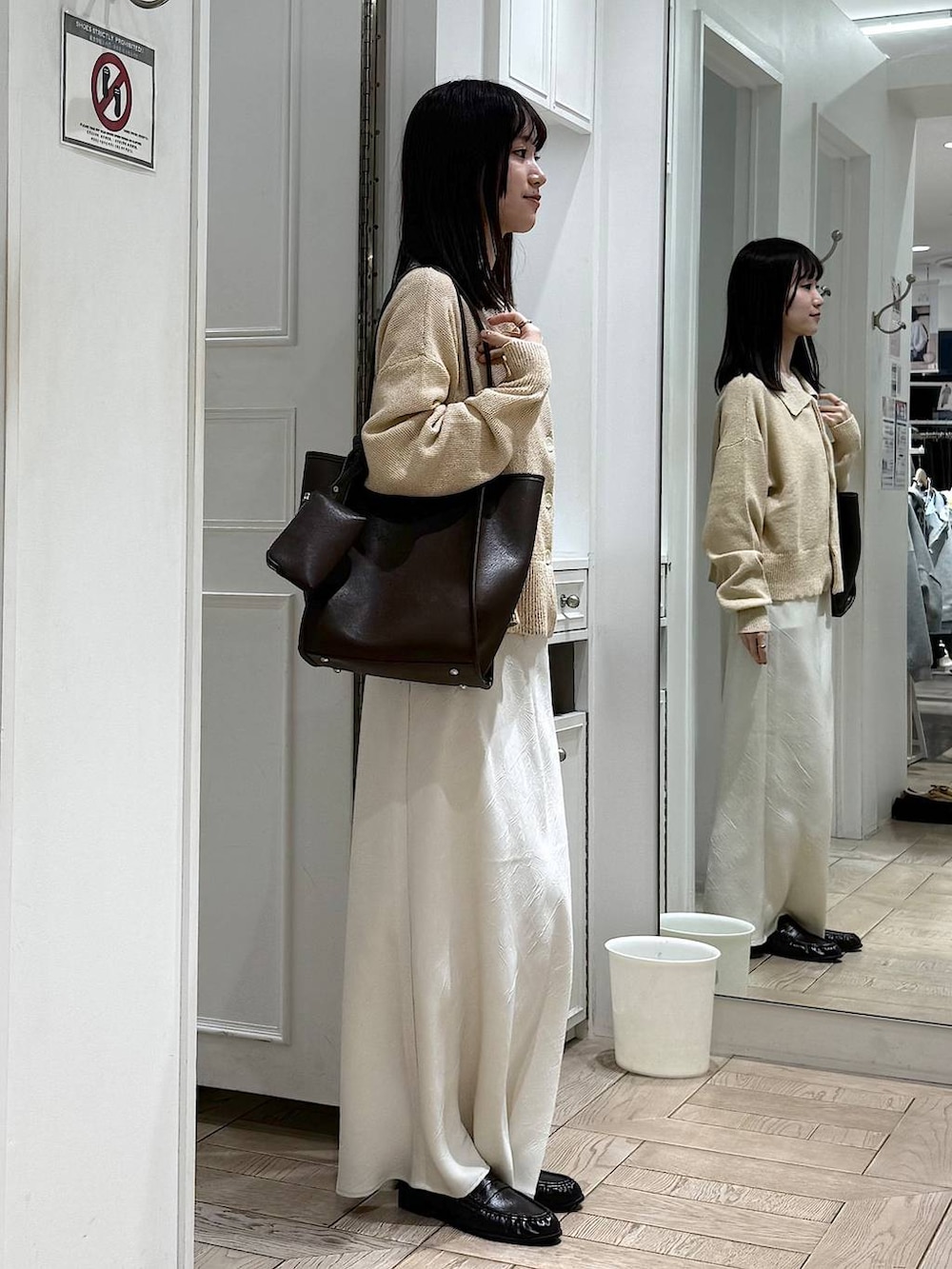 ホワイト系のスカート、ブラウン系のローファー、ブラウン系のトートバッグを着用したレディースの春コーディネートの2枚目の写真