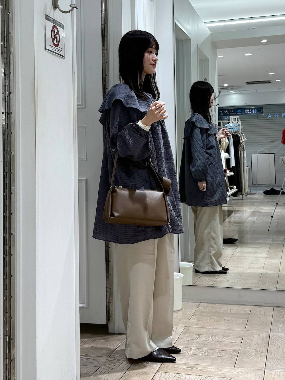 ホワイト系のスラックス、ブラウン系のサンダル、ブラウン系のショルダーバッグを着用したレディースの春コーディネートの2枚目の写真