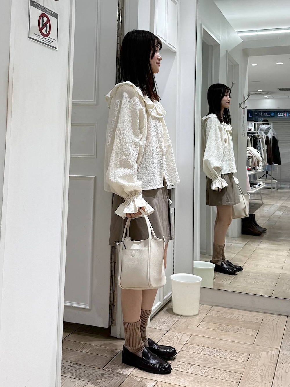 ホワイト系のショルダーバッグ、ブラウン系のローファー、ホワイト系のシャツ/ブラウスを着用したレディースの冬コーディネートの2枚目の写真