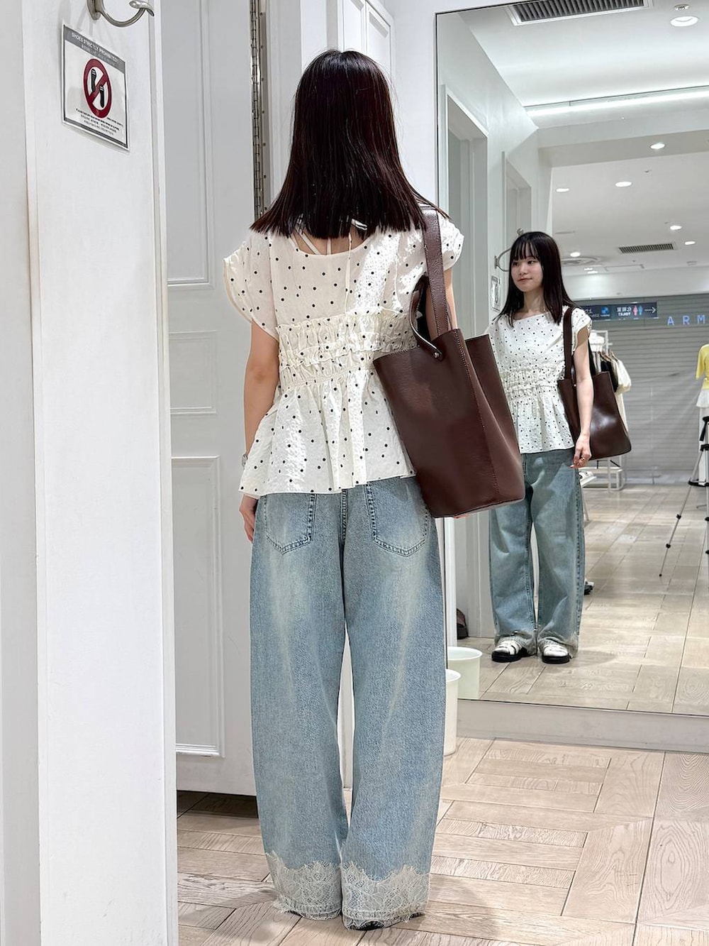ブルー系のデニムパンツ、ホワイト系のサンダル、ブラウン系のトートバッグを着用したレディースの夏コーディネートの3枚目の写真