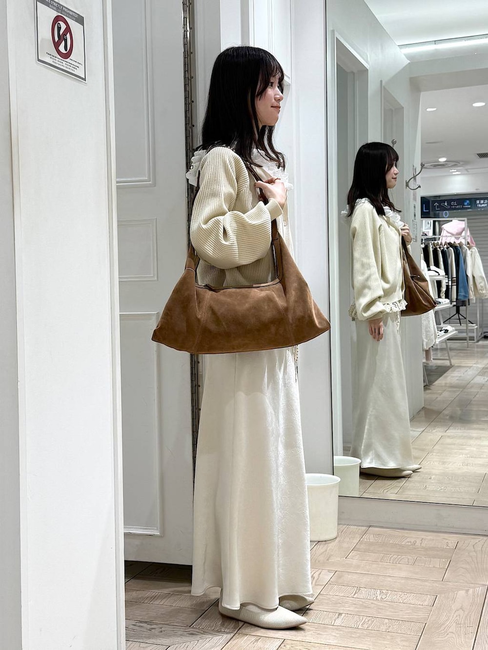 ホワイト系のスカート、ホワイト系のパンプス、ブラウン系のショルダーバッグを着用したレディースの冬コーディネートの2枚目の写真