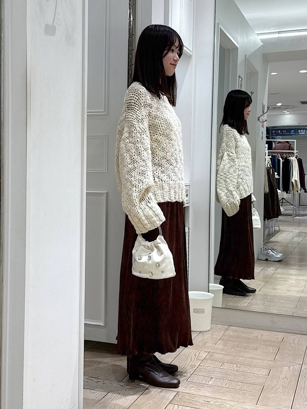 ブラウン系のスカート、ホワイト系のニット/セーター、ブラウン系のブーツを着用したレディースの冬コーディネートの2枚目の写真