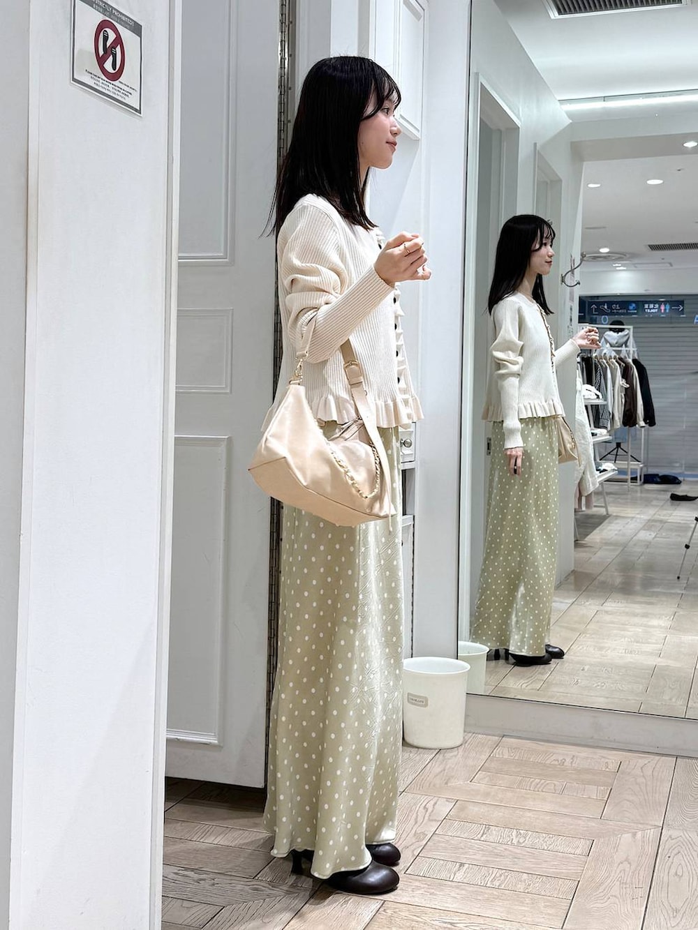 ベージュ系のスカート、ベージュ系のショルダーバッグ、ブラウン系のサンダルを着用したレディースの冬コーディネートの2枚目の写真