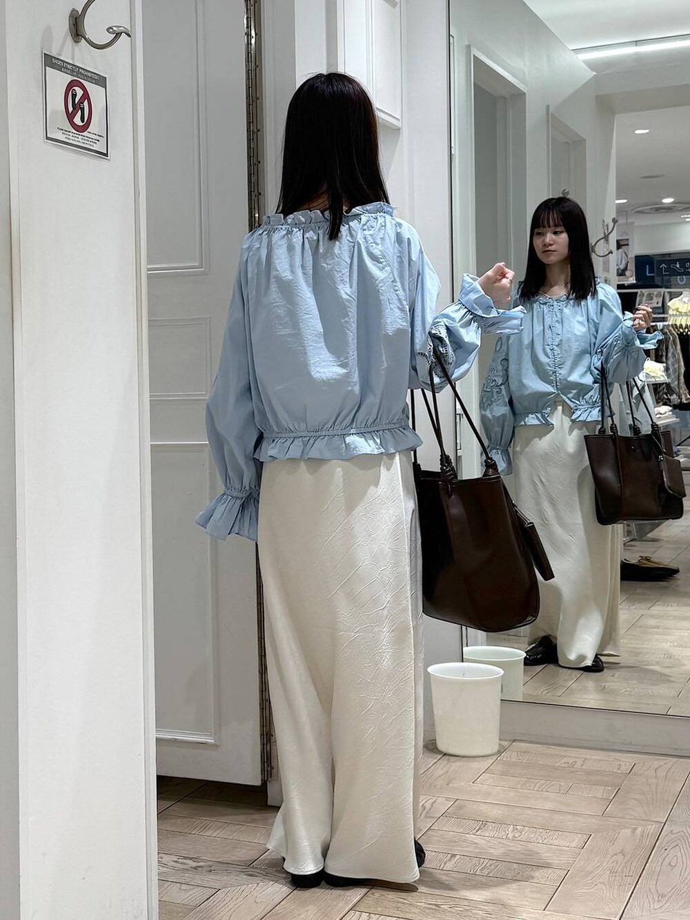 ホワイト系のスカート、ブラウン系のローファー、ブラウン系のトートバッグを着用したレディースの春コーディネートの3枚目の写真