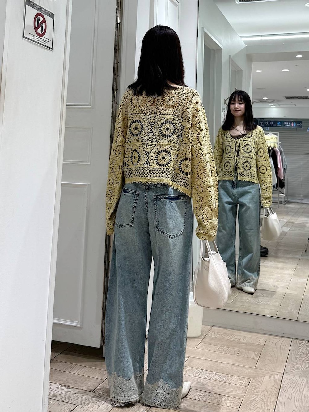 ホワイト系のショルダーバッグ、ブルー系のデニムパンツ、ホワイト系のパンプスを着用したレディースの春コーディネートの3枚目の写真