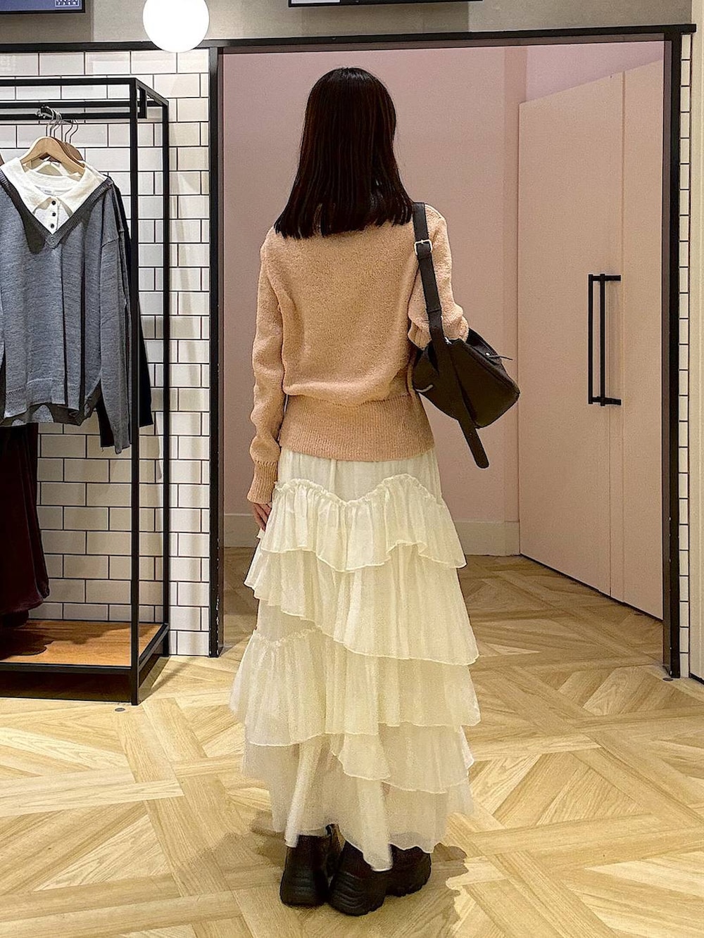 ブラウン系のショルダーバッグ、ホワイト系のスカート、ピンク系のニット/セーターを着用したレディースの秋コーディネートの3枚目の写真