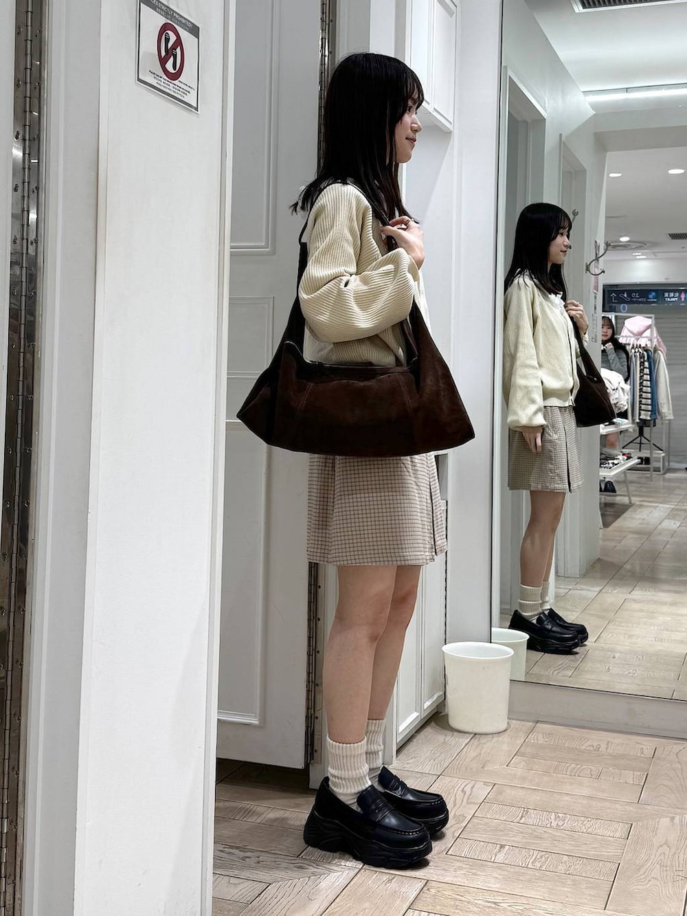 ブラック系のローファー、ブラウン系のショルダーバッグ、ベージュ系のカーディガン/ボレロを着用したレディースの冬コーディネートの2枚目の写真