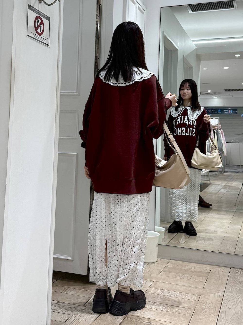 ベージュ系のショルダーバッグ、ブラウン系のローファー、ホワイト系のスカートを着用したレディースの冬コーディネートの3枚目の写真