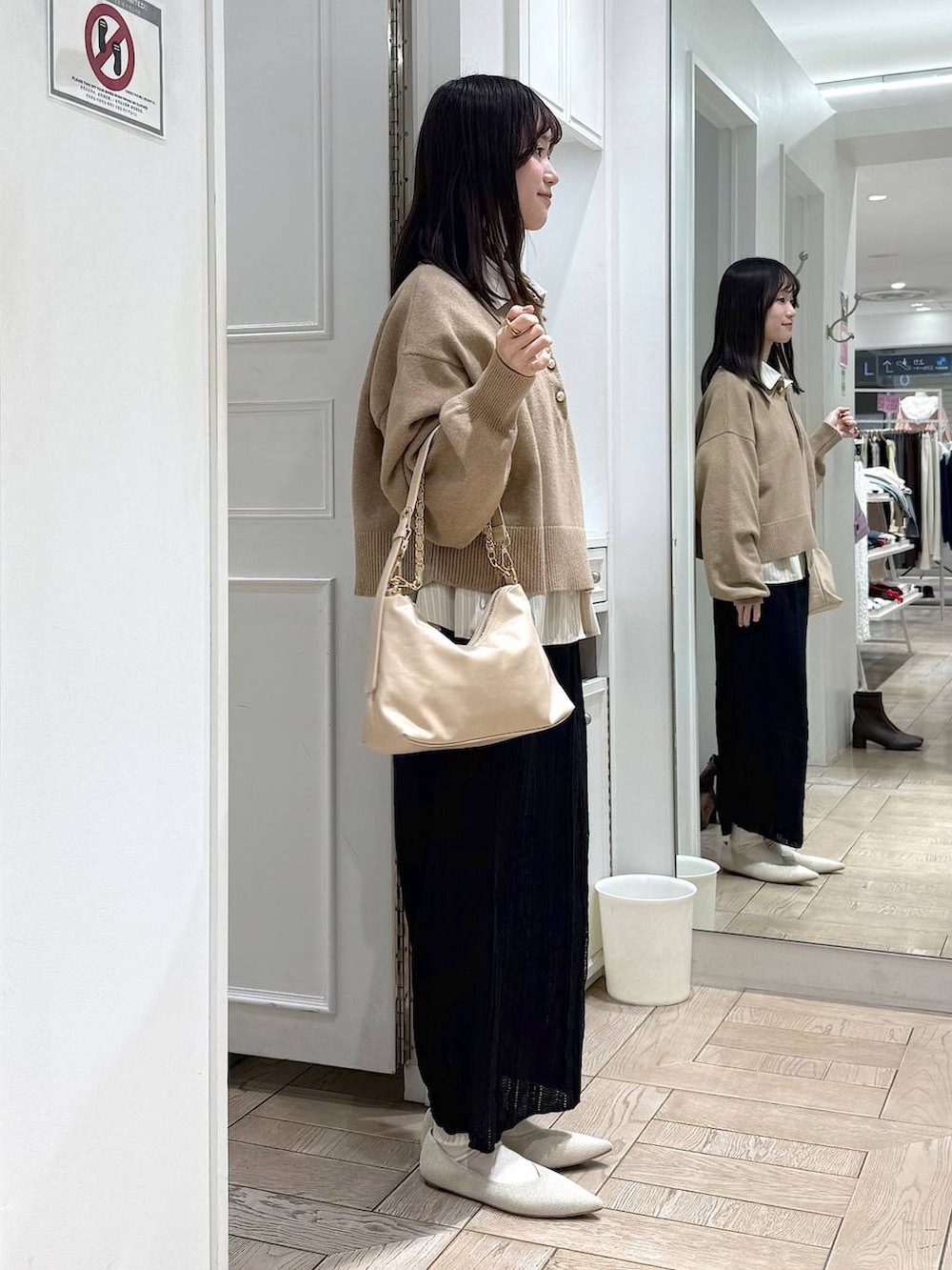 ベージュ系のショルダーバッグ、ホワイト系のパンプス、ブラック系のスカートを着用したレディースの冬コーディネートの2枚目の写真