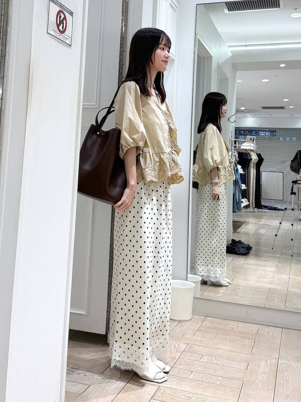 ベージュ系のシャツ/ブラウス、ブラウン系のトートバッグ、ホワイト系のサンダルを着用したレディースの夏コーディネートの2枚目の写真