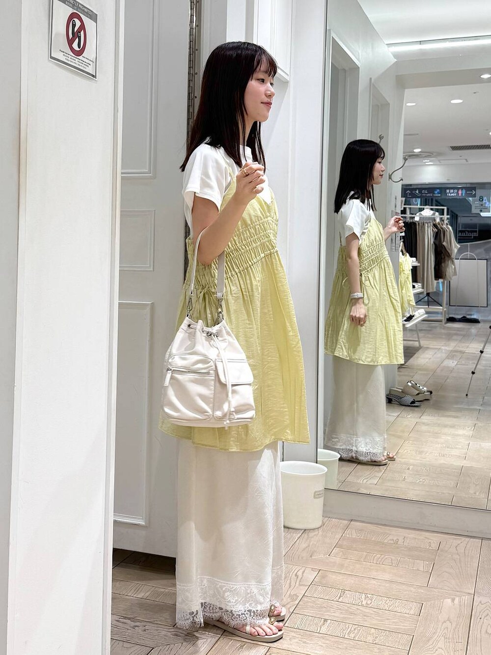 イエロー系のワンピース、ホワイト系のTシャツ/カットソー、ホワイト系のサンダルを着用したレディースの夏コーディネートの2枚目の写真