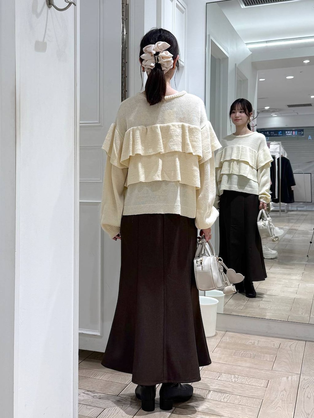 ブラウン系のスカート、ホワイト系のボストンバッグ、ブラック系のブーツを着用したレディースの冬コーディネートの3枚目の写真