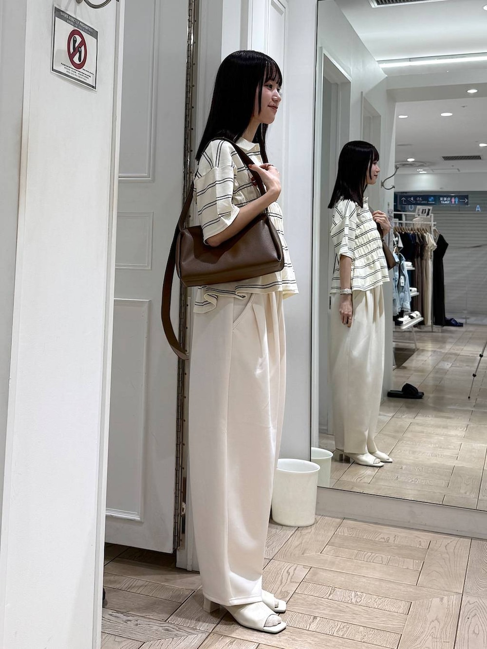 ベージュ系のスウェットパンツ、ブラウン系のショルダーバッグ、ホワイト系のサンダルを着用したレディースの春コーディネートの2枚目の写真