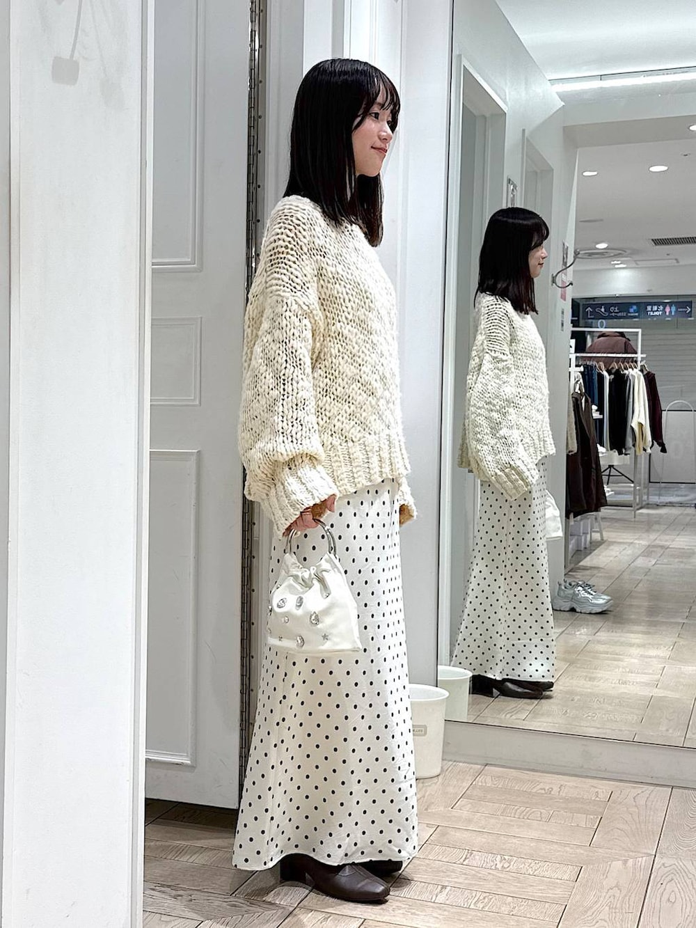 ホワイト系のスカート、ホワイト系のニット/セーター、ホワイト系のハンドバッグを着用したレディースの冬コーディネートの2枚目の写真