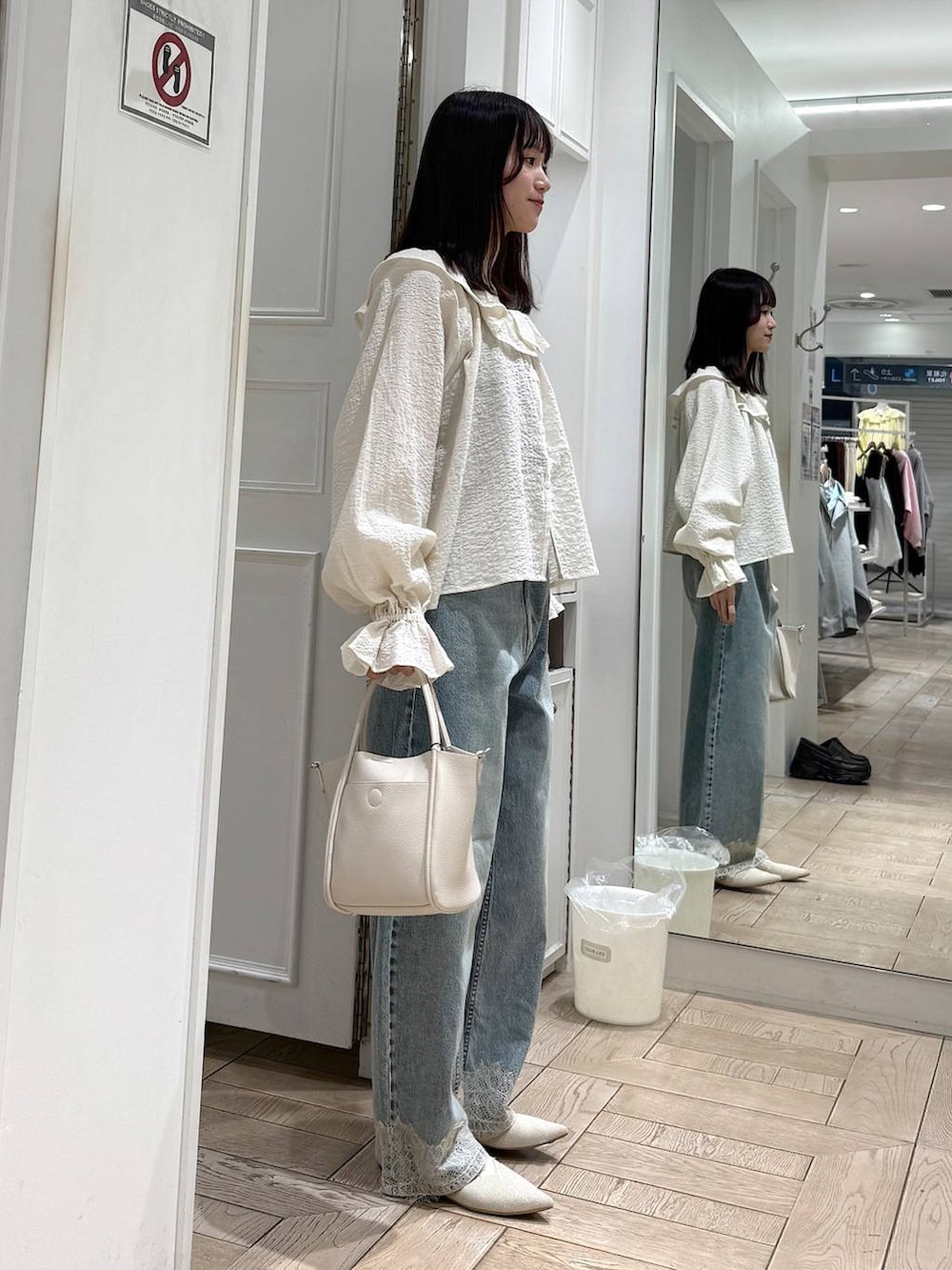 ホワイト系のショルダーバッグ、ブルー系のデニムパンツ、ホワイト系のパンプスを着用したレディースの春コーディネートの2枚目の写真