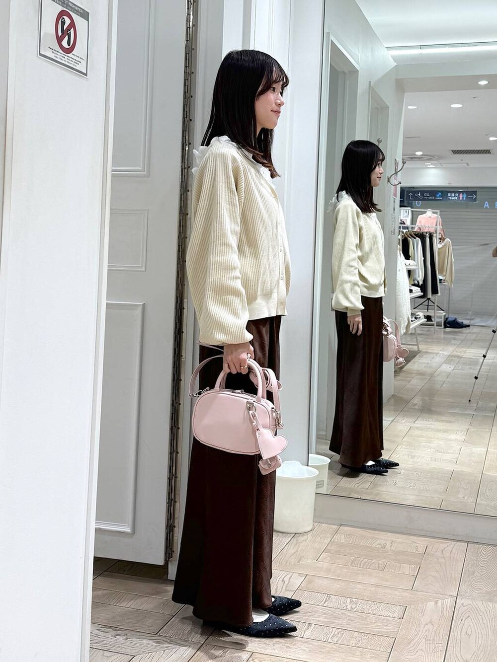 ブラウン系のスカート、ブラック系のパンプス、ピンク系のボストンバッグを着用したレディースの冬コーディネートの2枚目の写真