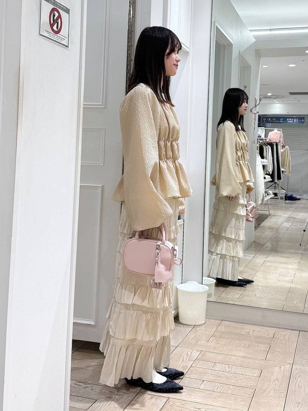 ブラック系のパンプス、ピンク系のボストンバッグ、ホワイト系のスカートを着用したレディースの冬コーディネートの2枚目の写真