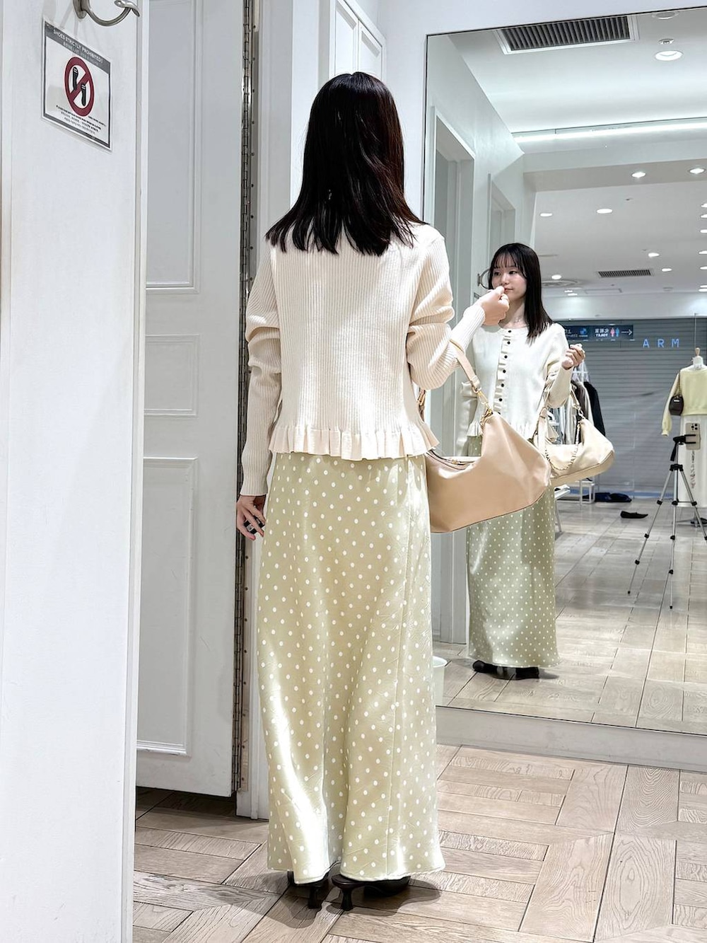 ベージュ系のスカート、ベージュ系のショルダーバッグ、ブラウン系のサンダルを着用したレディースの冬コーディネートの3枚目の写真