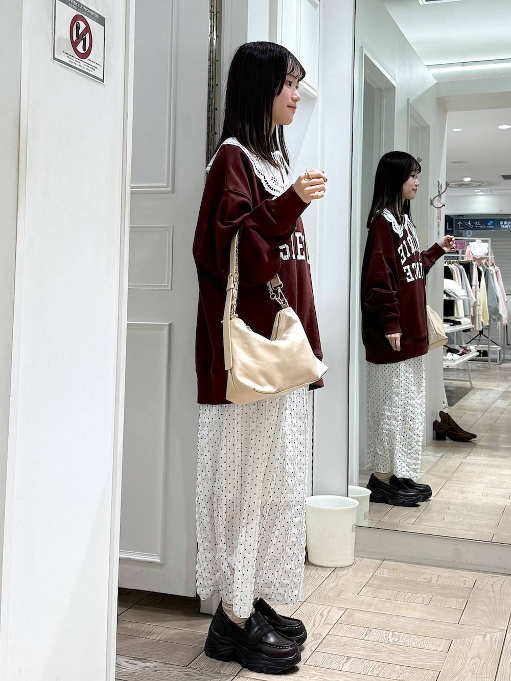 ベージュ系のショルダーバッグ、ブラウン系のローファー、ホワイト系のスカートを着用したレディースの冬コーディネートの2枚目の写真