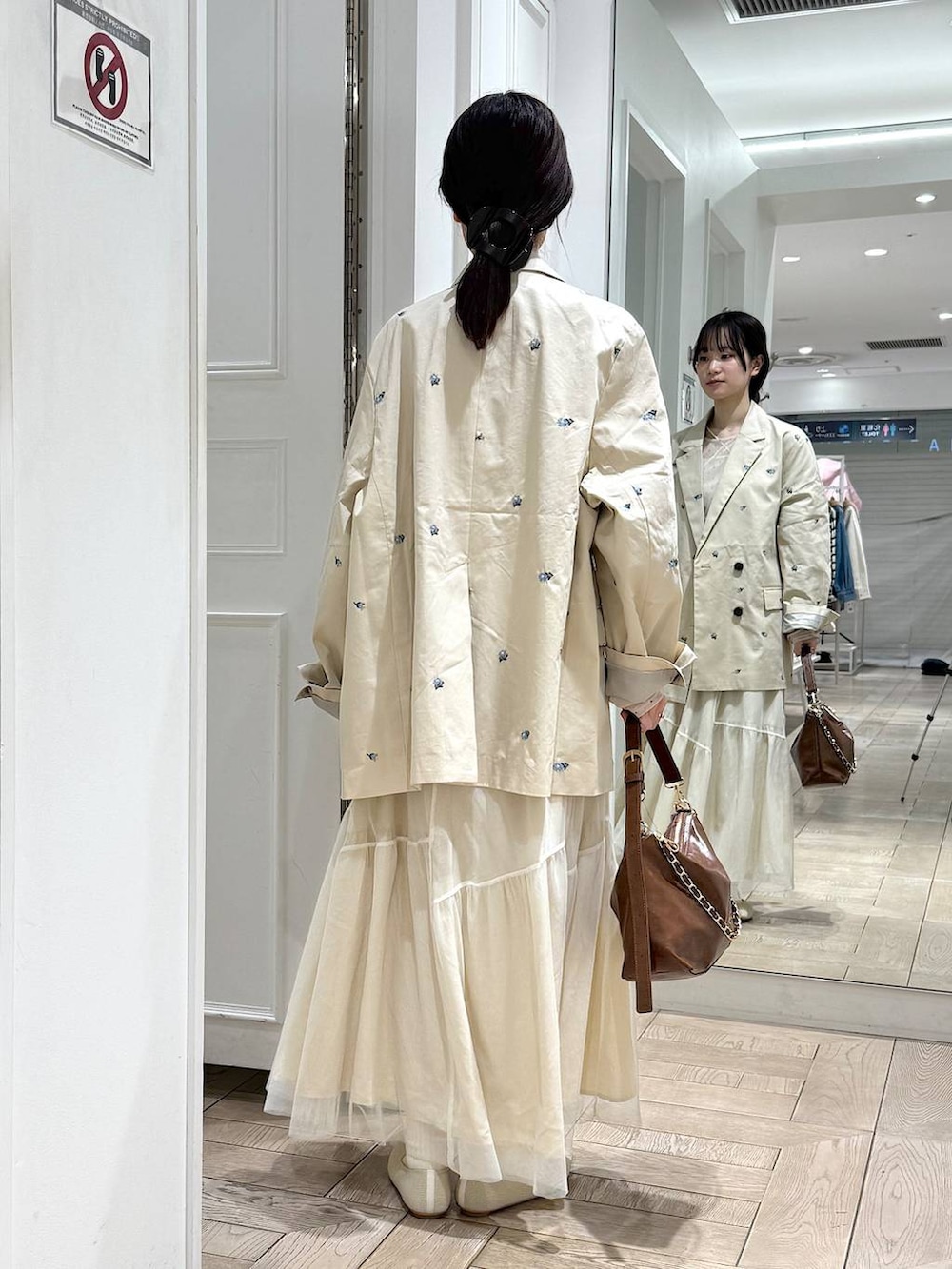 ブラウン系のショルダーバッグ、ホワイト系のパンプス、ホワイト系のスカートを着用したレディースの冬コーディネートの3枚目の写真