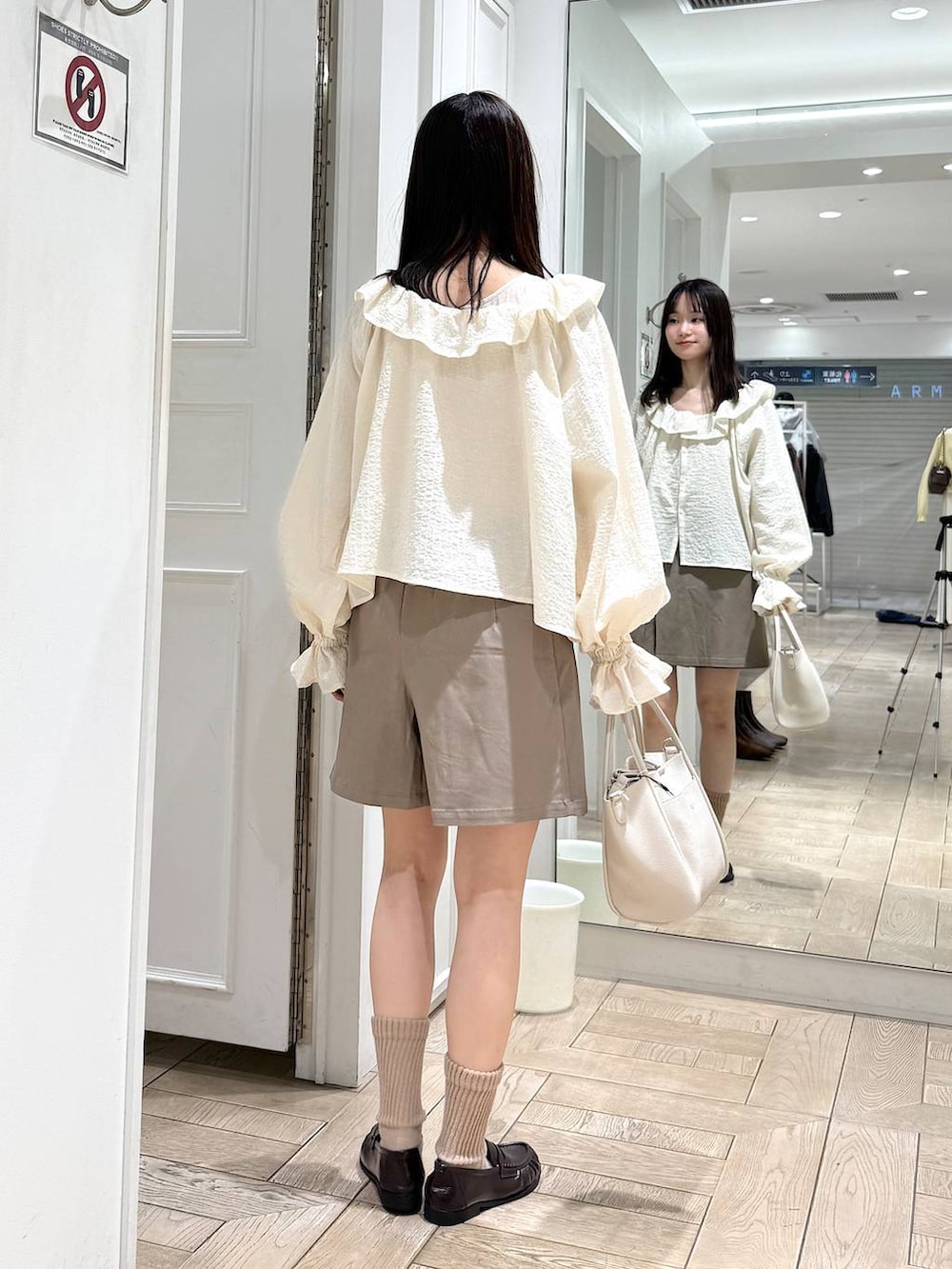 ホワイト系のショルダーバッグ、ブラウン系のローファー、ホワイト系のシャツ/ブラウスを着用したレディースの冬コーディネートの3枚目の写真