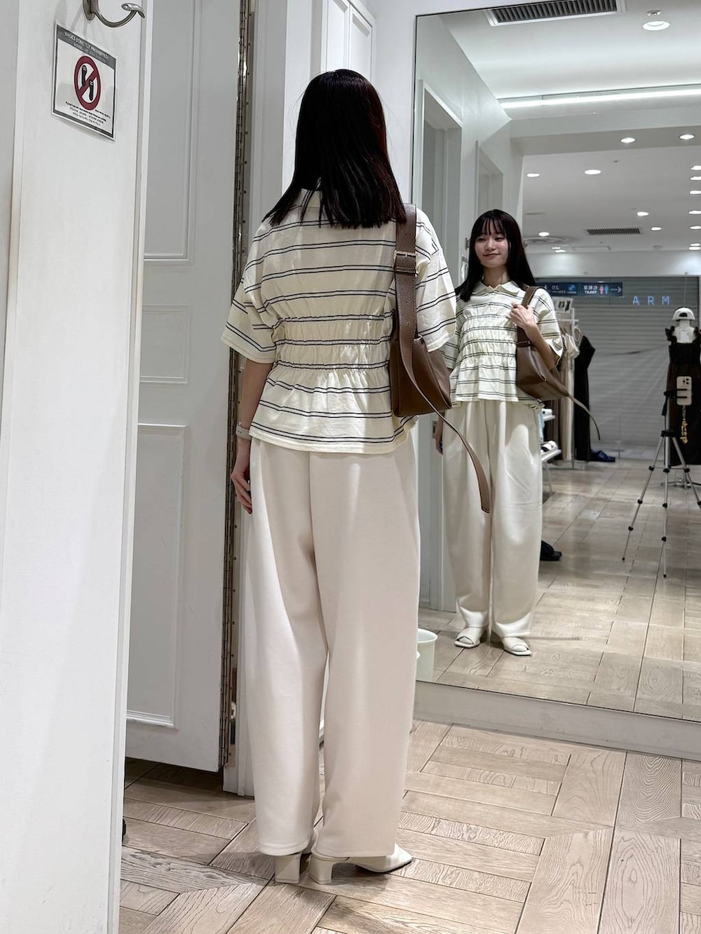 ベージュ系のスウェットパンツ、ブラウン系のショルダーバッグ、ホワイト系のサンダルを着用したレディースの春コーディネートの3枚目の写真
