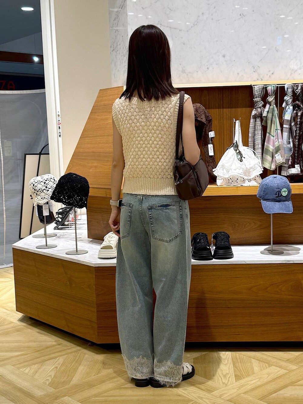 ホワイト系のベスト、ブルー系のデニムパンツ、ホワイト系のサンダルを着用したレディースの夏コーディネートの3枚目の写真