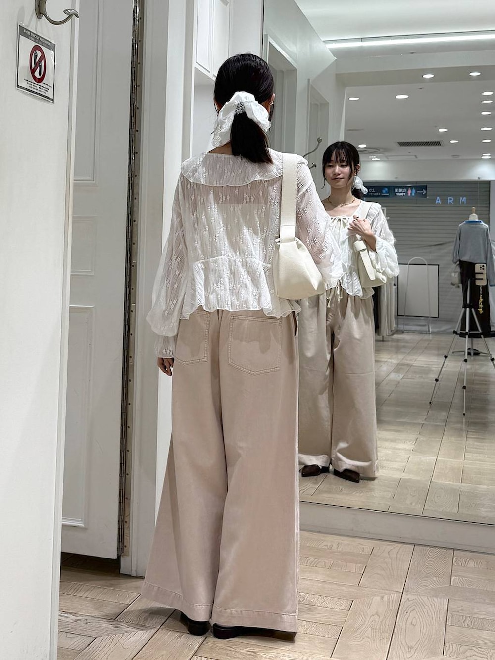 ピンク系のデニムパンツ、ブラウン系のサンダル、ホワイト系のショルダーバッグを着用したレディースの春コーディネートの3枚目の写真