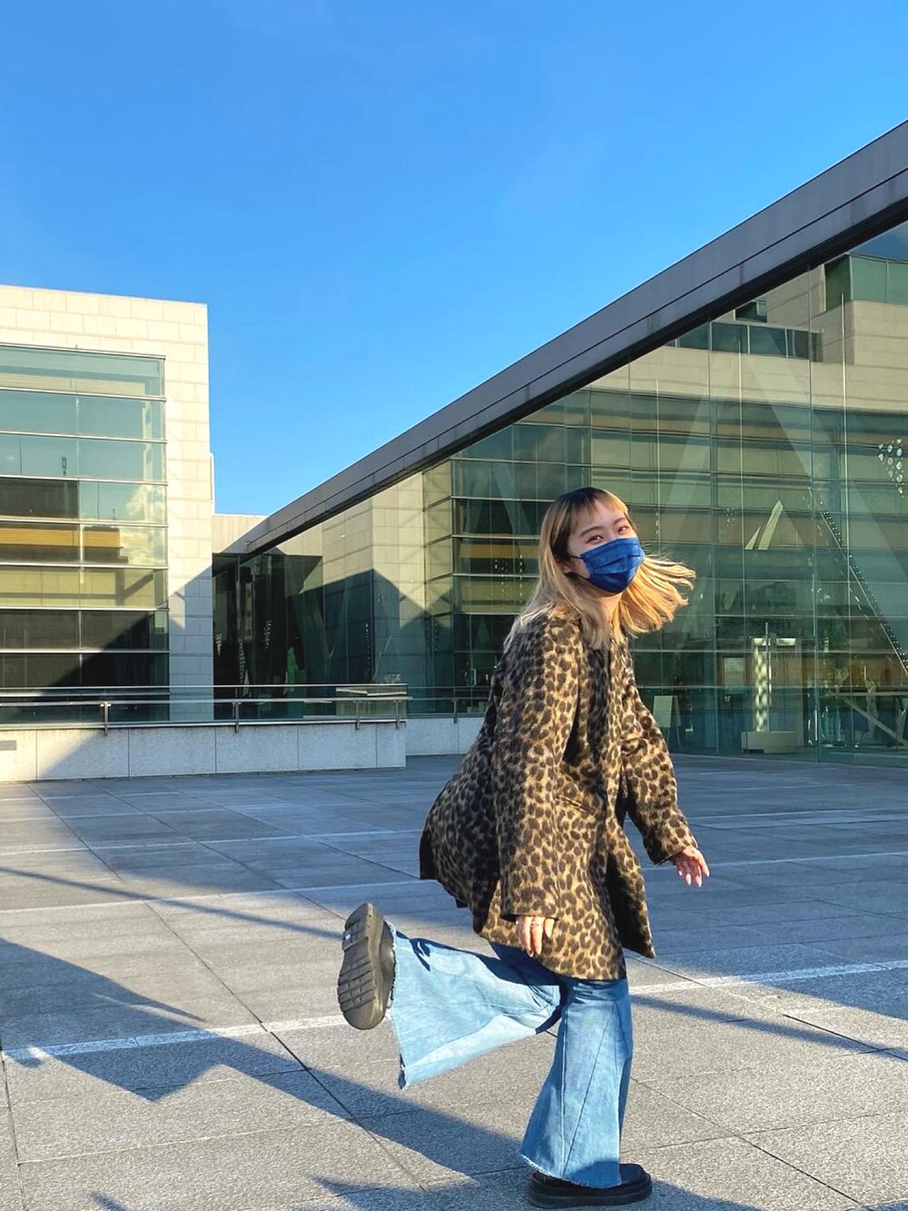 ブラウン系のノーカラージャケット、ブラック系のニット/セーター、ブルー系のデニムパンツを着用したレディースの春コーディネートの2枚目の写真