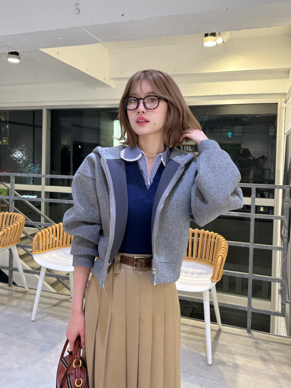 ブラウン系のショルダーバッグ、ベージュ系のスカート、ブルー系のトップスを着用したレディースの春コーディネートの4枚目の写真