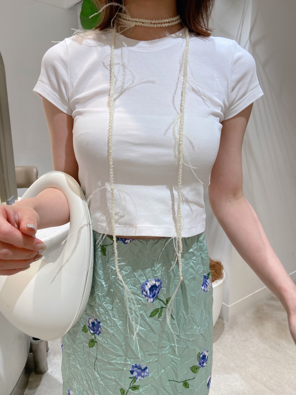 グリーン系のスカート、ホワイト系のハンドバッグ、ホワイト系のTシャツ/カットソーを着用したレディースの夏コーディネートの3枚目の写真